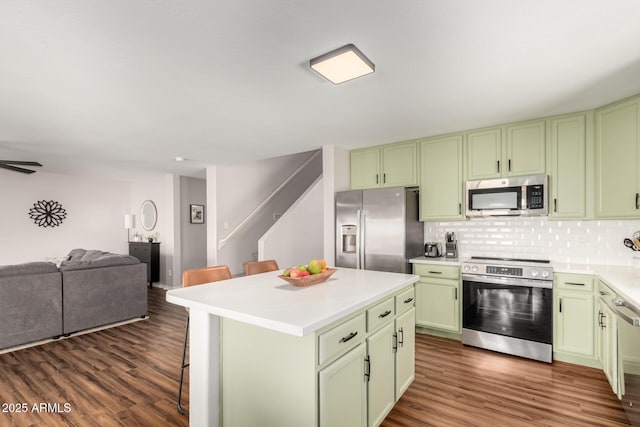 kitchen with appliances with stainless steel finishes, a breakfast bar, dark wood-type flooring, and green cabinets