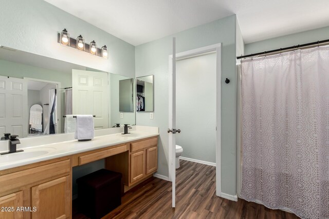 full bathroom with double vanity, toilet, a sink, and wood finished floors