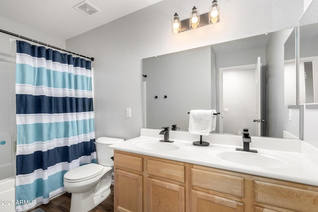 bathroom with toilet, double vanity, visible vents, and a sink