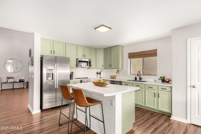 kitchen featuring a sink, green cabinets, light countertops, appliances with stainless steel finishes, and tasteful backsplash