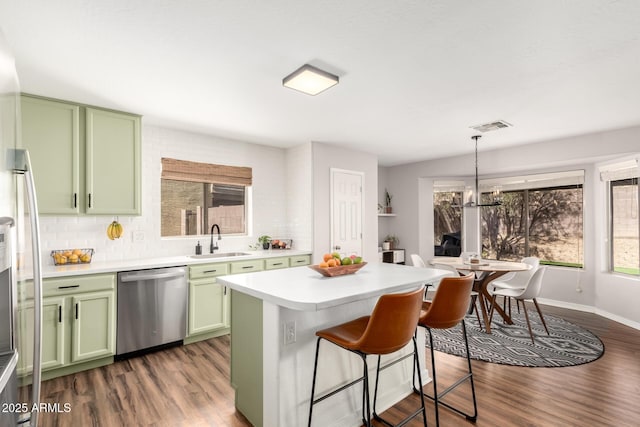 kitchen featuring stainless steel dishwasher, light countertops, a sink, and green cabinets