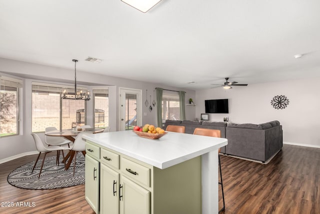 kitchen with baseboards, a kitchen island, visible vents, and dark wood-type flooring