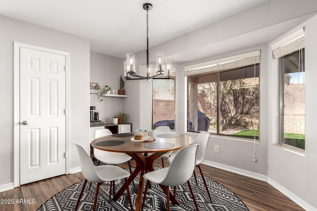 dining area featuring baseboards, wood finished floors, and a notable chandelier