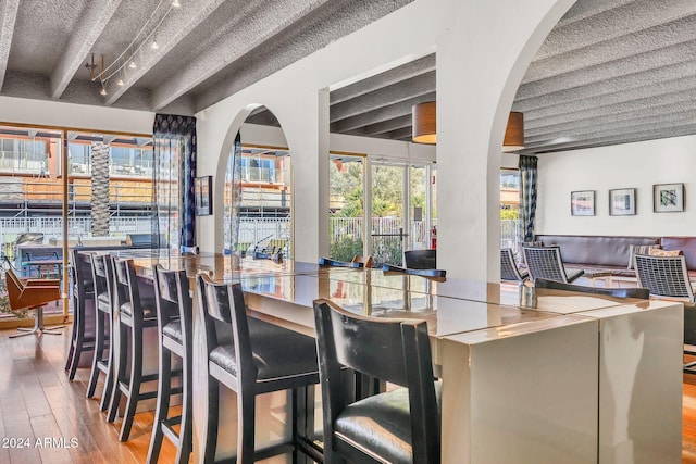 dining space with beamed ceiling and wood-type flooring