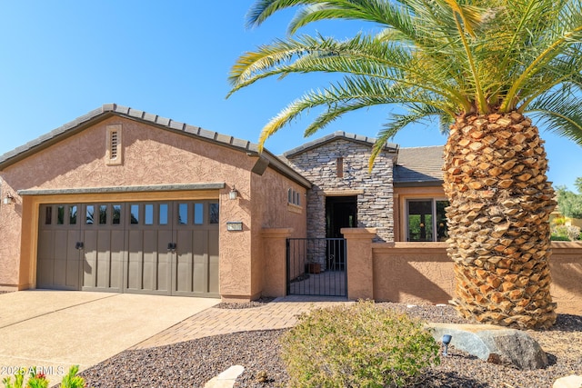 view of front of house featuring stucco siding, a fenced front yard, stone siding, concrete driveway, and an attached garage