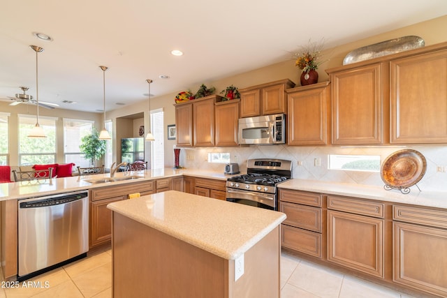 kitchen with a kitchen island, light tile patterned floors, decorative backsplash, stainless steel appliances, and a sink