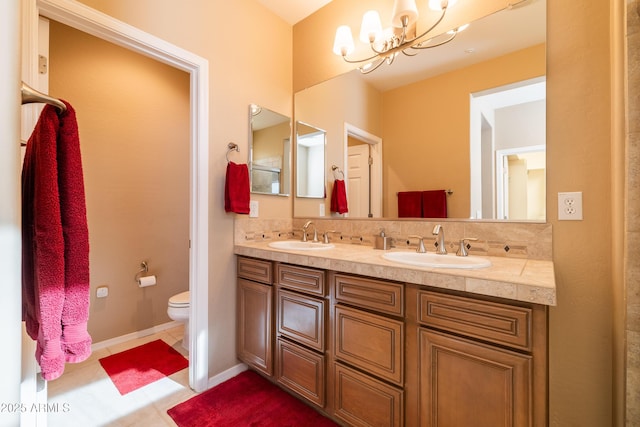 bathroom featuring double vanity, toilet, baseboards, and a sink