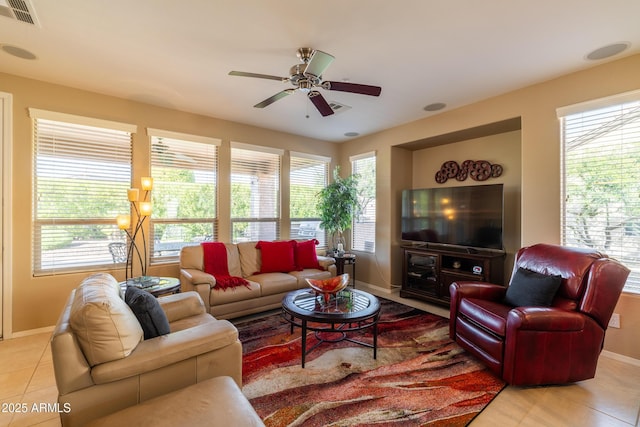 living room featuring light tile patterned flooring, a ceiling fan, visible vents, and baseboards