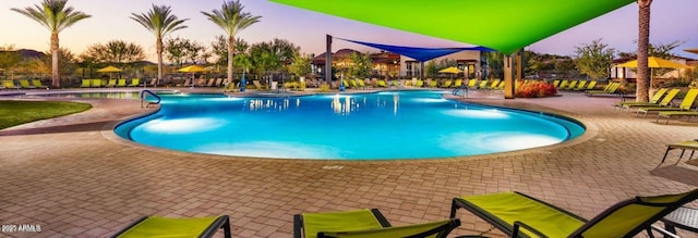 pool at dusk featuring a patio and a community pool