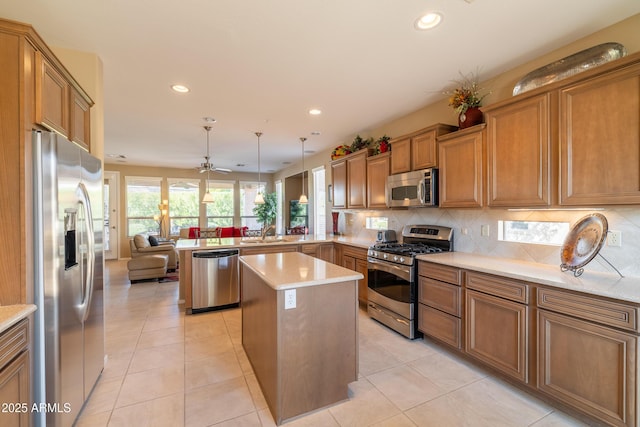 kitchen with decorative backsplash, brown cabinets, a peninsula, stainless steel appliances, and a sink