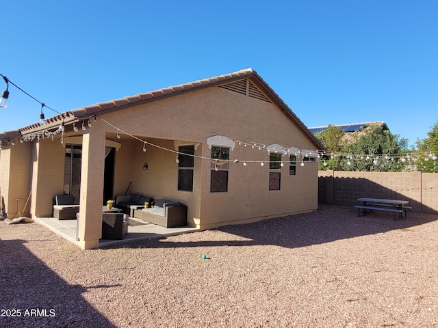 back of property with stucco siding, an outdoor hangout area, a patio, and fence