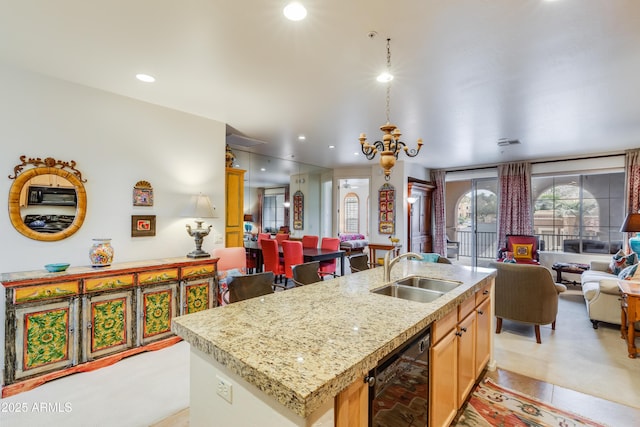 kitchen featuring a sink, open floor plan, recessed lighting, and a center island with sink