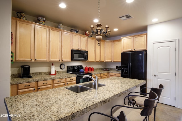 kitchen featuring light brown cabinetry, visible vents, black appliances, and a sink