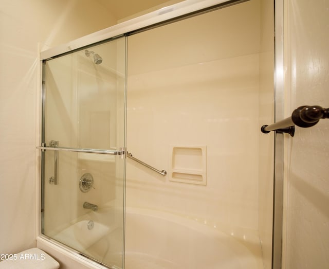 bathroom with toilet and combined bath / shower with glass door