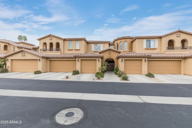 mediterranean / spanish home featuring stucco siding, a balcony, and driveway