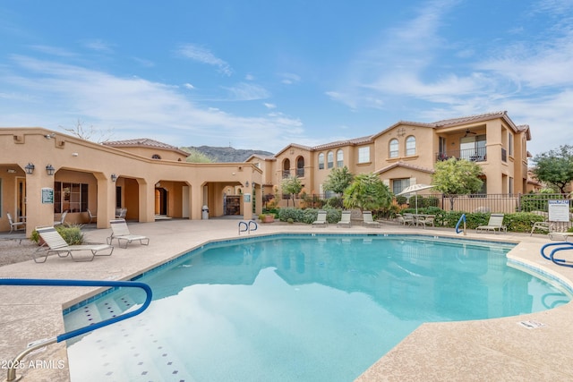 community pool with a patio and fence