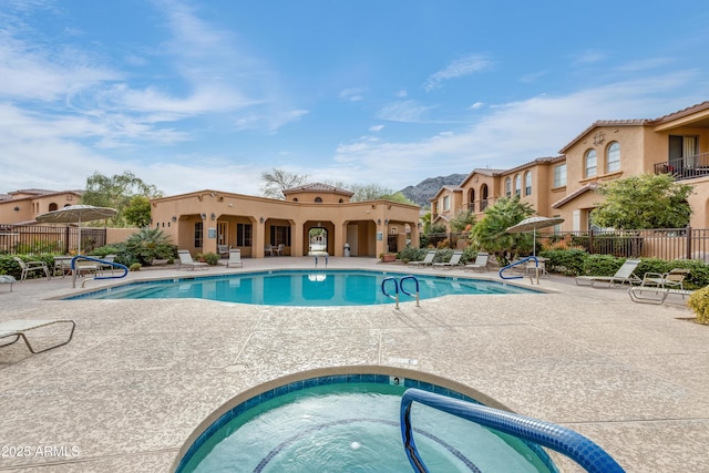 community pool featuring a community hot tub, a patio area, and fence