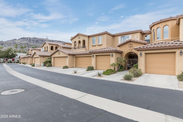 view of front of home featuring stucco siding, a tiled roof, concrete driveway, and a garage