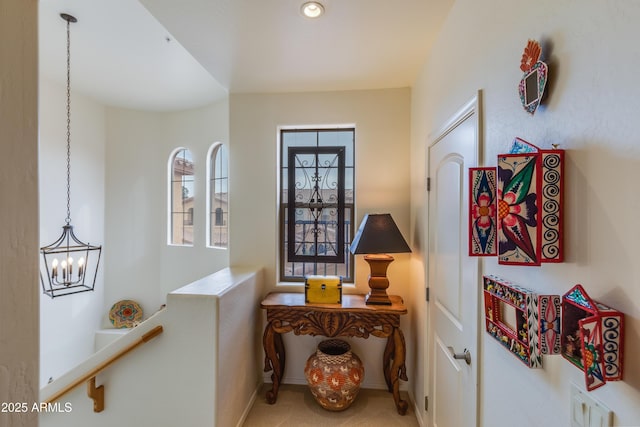 hall featuring an inviting chandelier and baseboards