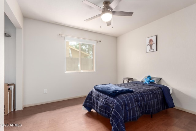 bedroom featuring wood finished floors, a ceiling fan, and baseboards