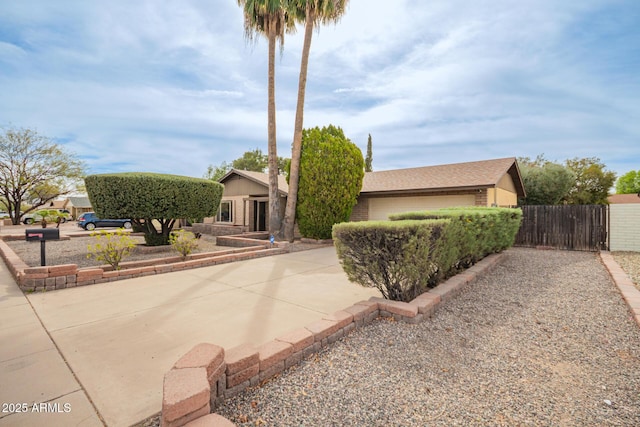 view of front of property featuring an attached garage, fence, concrete driveway, and brick siding