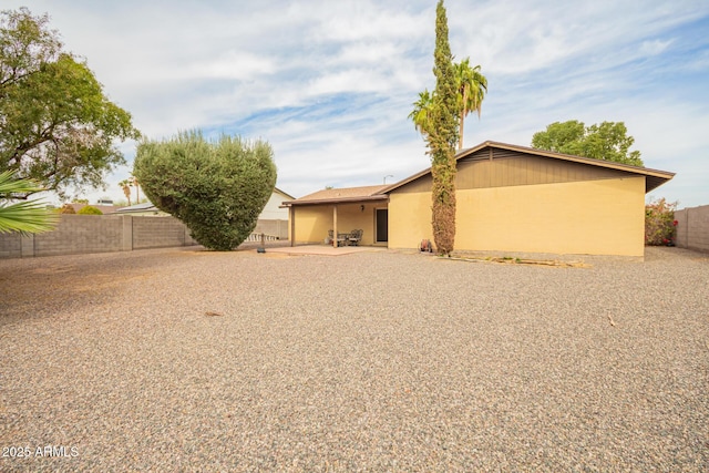 rear view of house featuring a patio area, a fenced backyard, and stucco siding