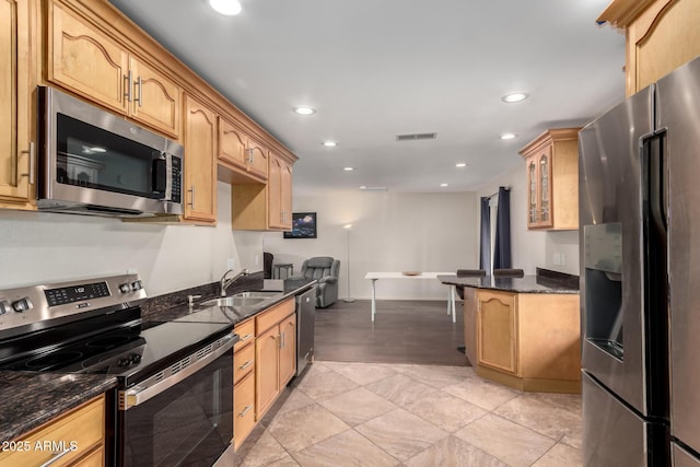 kitchen with stainless steel appliances, recessed lighting, glass insert cabinets, a sink, and dark stone countertops