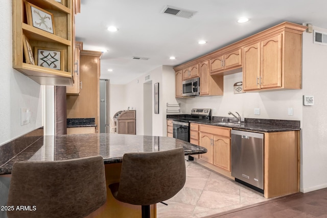 kitchen featuring recessed lighting, stainless steel appliances, a sink, visible vents, and dark stone counters