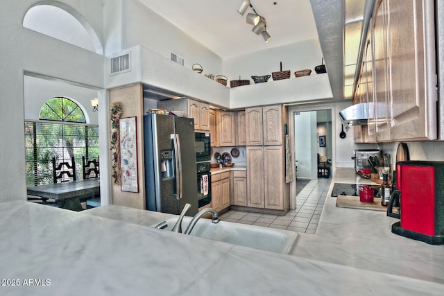 8120 E Cortez Dr, Scottsdale, AZ 85260 - kitchen with black appliances, a towering ceiling, light countertops, light tile patterned flooring, and wall chimney exhaust hood