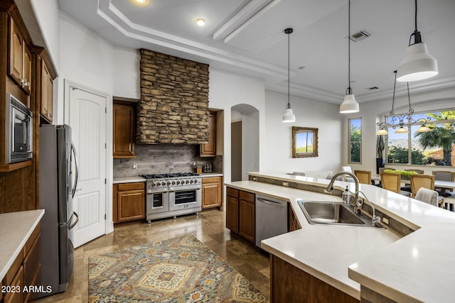 kitchen with sink, hanging light fixtures, stainless steel appliances, backsplash, and a kitchen island with sink