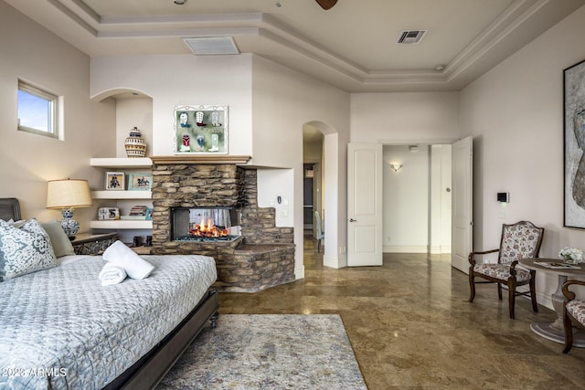 bedroom with a tray ceiling, ceiling fan, a fireplace, and a high ceiling