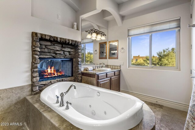 bathroom with a fireplace, vanity, and a relaxing tiled tub