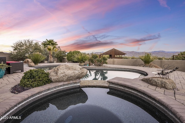 pool at dusk featuring a mountain view