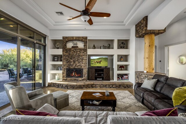 living room with ceiling fan, built in features, and a fireplace
