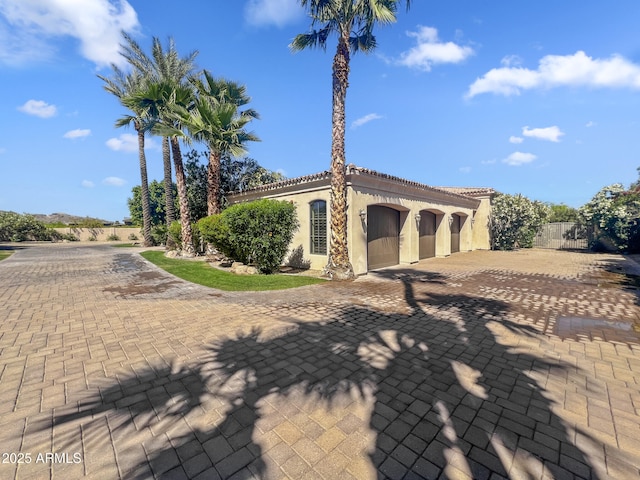 view of front facade featuring fence, an attached garage, driveway, and stucco siding
