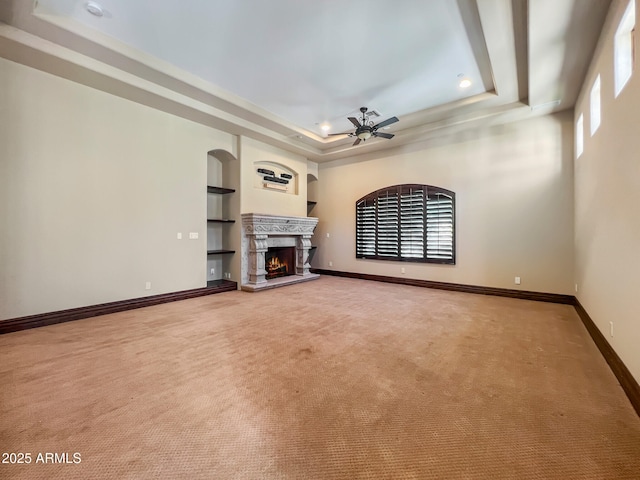 unfurnished living room with plenty of natural light, ceiling fan, and a tray ceiling