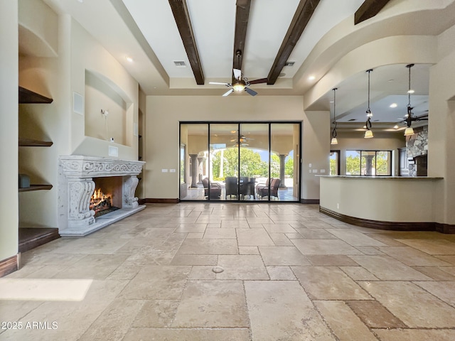 unfurnished living room with baseboards, a ceiling fan, a warm lit fireplace, and stone tile flooring