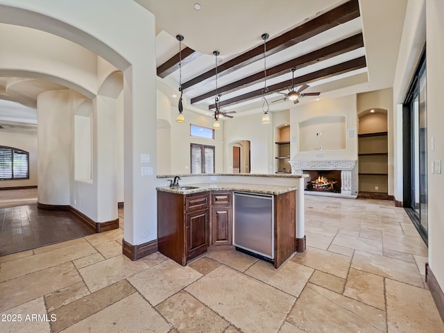 kitchen featuring stone tile flooring, built in features, baseboards, light stone counters, and a sink