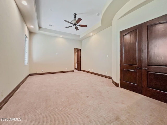 unfurnished bedroom with light colored carpet, a raised ceiling, baseboards, and visible vents
