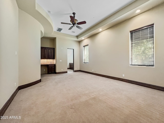 spare room featuring light colored carpet, ceiling fan, visible vents, and baseboards