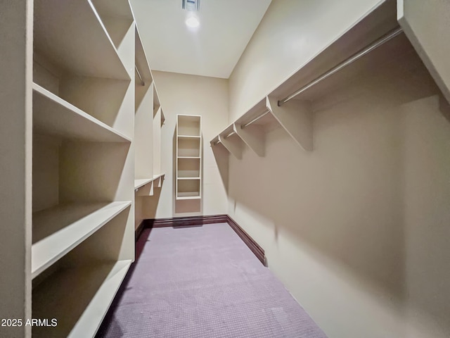 spacious closet with dark carpet and visible vents