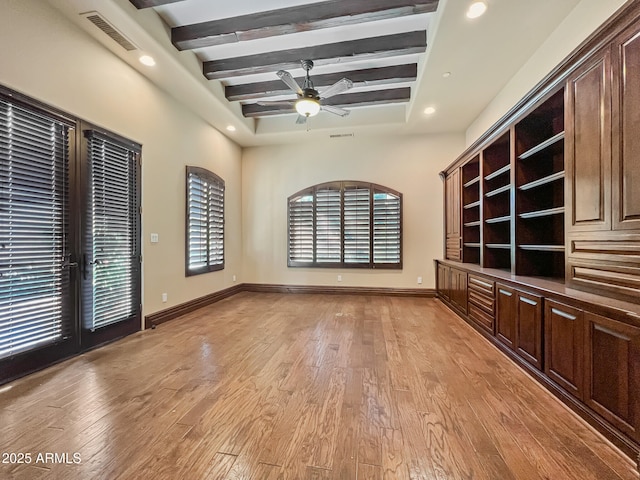 unfurnished living room with ceiling fan, visible vents, beam ceiling, and light wood-style floors