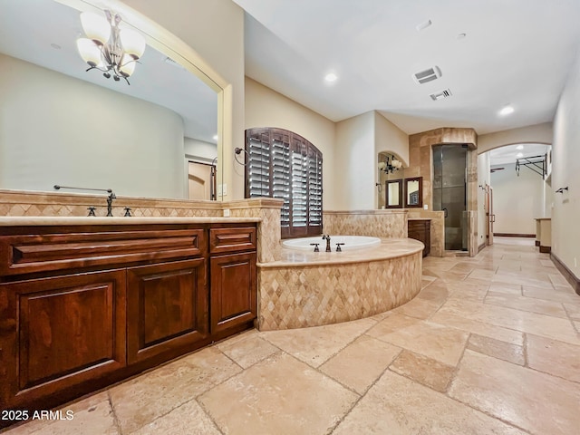 bathroom with a bath, visible vents, a stall shower, vanity, and stone tile floors