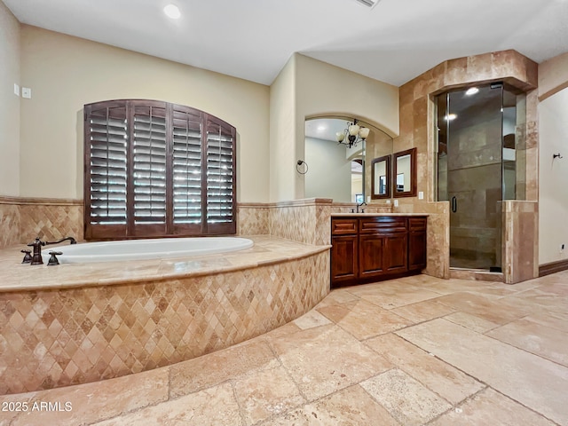 full bath with a garden tub, stone tile flooring, vanity, a chandelier, and a stall shower