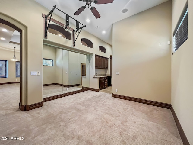 empty room with ceiling fan, light carpet, arched walkways, recessed lighting, and baseboards