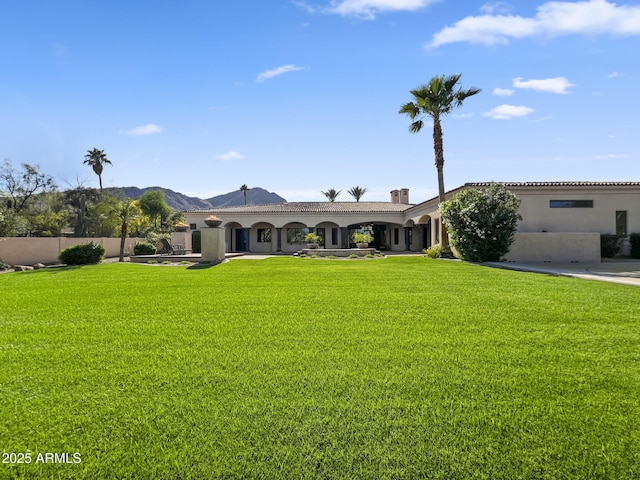 view of front of property with a mountain view, a front lawn, and stucco siding