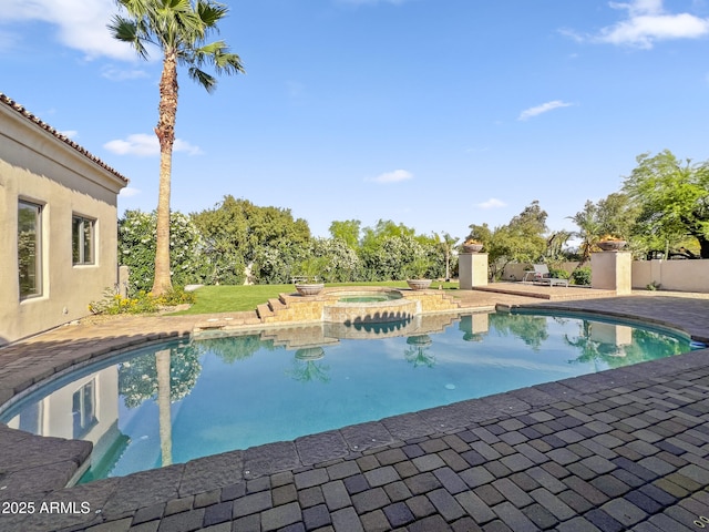 outdoor pool with an in ground hot tub and a patio area