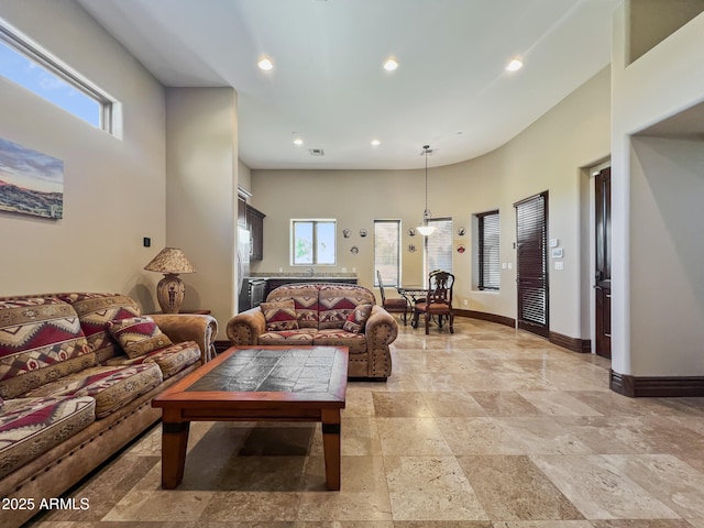 living area featuring recessed lighting, stone tile floors, baseboards, and a wealth of natural light