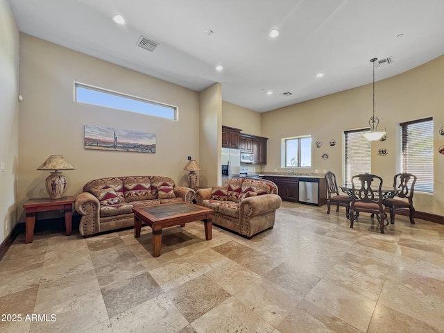 living room featuring stone tile floors, recessed lighting, baseboards, and visible vents