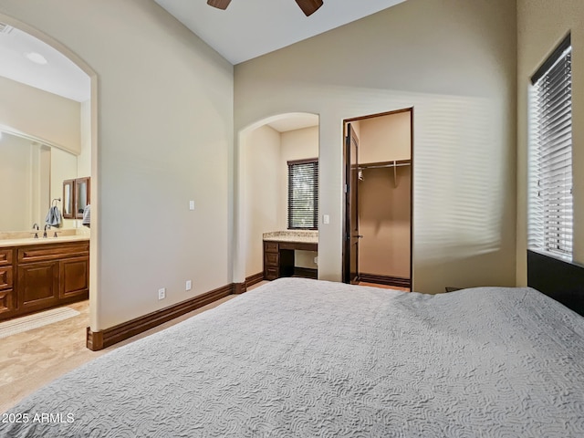 bedroom featuring ensuite bathroom, arched walkways, vaulted ceiling, and a spacious closet